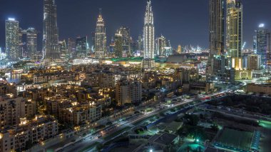 Dubai Şehir Merkezi Ufuk Çizgisi gecesi Burj Halife ve Dubai 'deki diğer panoramik manzaralı Birleşik Arap Emirlikleri. Çember yollarda ve çeşmelerde trafik vardı. Geleneksel ve modern binalar.