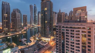 Aerial panoramic view of Dubai Marina residential and office skyscrapers with waterfront night to day transition timelapse before sunrise. Floating boats and yachts clipart