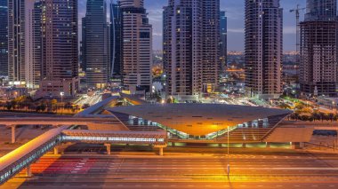 Dubai Marina 'dan Şeyh Zayed yoluna gece gündüz aydınlık gökdelenlerle geçiş zamanı, Dubai. Trafik, yaya köprüsü ve metro istasyonu. Birleşik Arap Emirlikleri