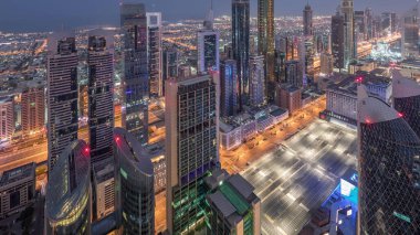 Sheikh Zayed Yolu yakınlarındaki binaların silueti ve Dubai, BAE 'deki hava trafiği gece gündüz değişiyor. Gündoğumundan önce finans merkezinde ve şehir merkezinde modern kuleler ve aydınlık gökdelenler