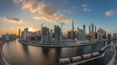 City center at sunset near river with bright illuminated skyscrapers day to night transition aerial timelapse in Business Bay and Downtown, Dubai, United Arab Emirates