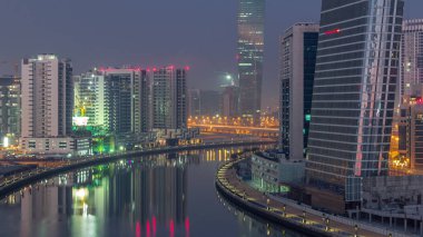 Gece gündüz kanal yakınlarındaki devasa gökdelenlerin hava görüntüsü Business Bay, Dubai, Birleşik Arap Emirlikleri 'ndeki geçiş zamanı..