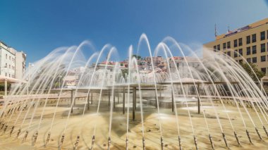 Lisbon şehir merkezinde Martim Moniz Meydanı 'ndaki çeşme. Tepelerde mavi gökyüzü olan tarihi binalar