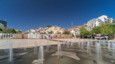 Lisbon şehir merkezinde Martim Moniz Meydanı 'ndaki çeşme. Tepelerde mavi gökyüzü olan tarihi binalar