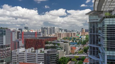 Singapur silueti Victoria caddesi ve Ulusal Kütüphane havadan zaman aralığı hipervanesi. Trafiği olan yeşil ağaçlar. Mavi gökyüzünde bulutlar