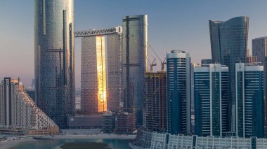 Abu Dabi 'deki Al Reem Adası' ndaki binalar yukarıdan zaman çizelgesi. Al Reem Adası 'nın akşamları gökdelenlerdeki yansımasını gösteren hava manzarası.