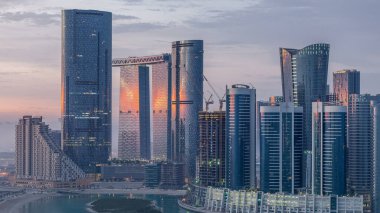 Skyscrapers on Al Reem in Abu Dhabi timelapse during sunrise from above. Aerial cityscape from Al Reem Island at morning with fog. Sun reflected on glass surface clipart