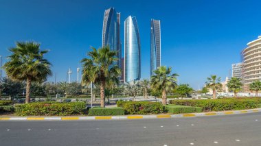 Ebu Dabi 'nin gökdelenleri Etihad Kuleleri' nin binaları zaman atlamalı. Avuç içleriyle ve trafiğiyle park et. Güneş cam yüzeyden yansıyor. Birleşik Arap Emirlikleri