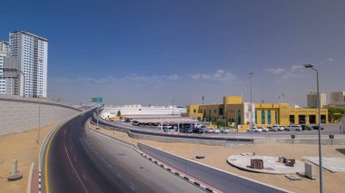Ajman 'da üst geçitte yol trafiği, köprüden gündüz vakti havadan görüntü. Birleşik Arap Emirlikleri 'nin arka planında kuleleri olan şehir manzarası.