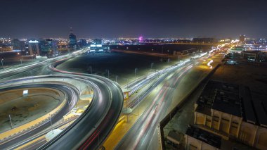 Panorama, Ajman hava sahasında büyük bir kavşakta trafiği gösteriyor. Gece vakti çatıdan görünüyor. Birleşik Arap Emirlikleri 'nde üst geçitle kesişen birçok araba var..