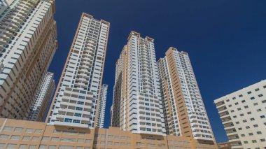 Ajman zaman ayarlı hiperhızlandırılmış modern yeni kuleler. Ajman 'ın yerleşim yeri ve ofis gökdelenleri olan şehir manzarası. Mavi gökyüzü. Birleşik Arap Emirlikleri.