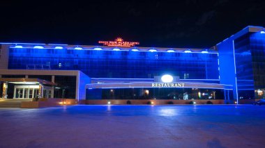 Aktau 'nun otel ve restoranlı gece hiperlapası. Aydınlatılmış Binalar Kazakistan 'ın Canlı Yüreğinde Akşam Gökyüzünü aydınlatıyor