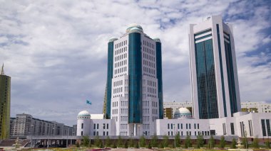Nur-Sultan şehrinde Kazakistan Cumhuriyeti Senatosu 'nun binaları aşırı hız kazanmıştır. Ön planda çiçek açmış. Arka planda Nurzhol Bulvarı. Yazın mavi bulutlu gökyüzü