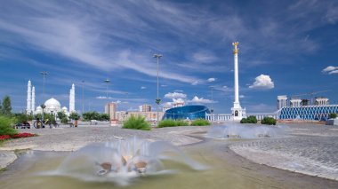 Independence Meydanı 'ndaki Çeşme hiperhızlandırılmış zaman aşımı. Yıldız heykeli Kazak Eli ve Kazak Ulusal Sanat Üniversitesi 'nin arka planında cami var. Nur-Sultan şehri, Kazakistan