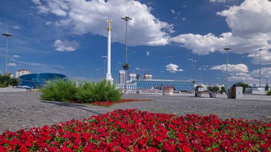 Yıldız heykeli Kazak Eli 'ın kuş Samruk ve Bağımsızlık Sarayı' nın zaman atlaması ve kırmızı çiçek tarhı ön planda. Nur-Sultan şehri, Kazakistan