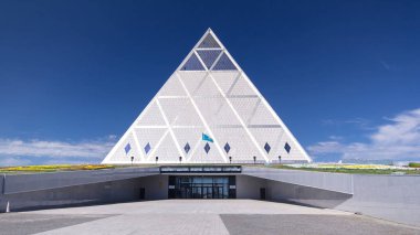 Entrance of the Palace of Peace and Reconciliation building timelapse hyperlapse with park and fountains near by. Kazakhstan, Nur-Sultan city clipart