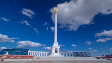 Kazakistan 'ın başkenti Astana' daki Independence Meydanı 'ndaki Kazak Eli Anıtı' nın zaman atlaması görüntüsü. Alttaki çiçek tarhında. Yaz günü mavi bulutlu bir gökyüzü. Nur-Sultan şehri