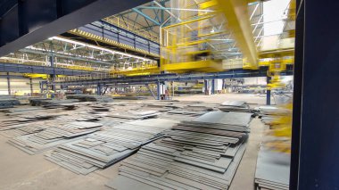 Factory workshop with lifting crane device timelapse hyperlapse, lift loads using lifting magnet, mechanical workshop, metal sheets structures on the floor of plant.
