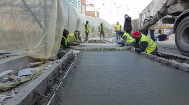 Çelik takviyesi yaptıktan sonra beton karıştırıcı zaman aşımına uğrayarak yolu hızlandırmak için hazır beton dökülüyor. Çadırla kaplı yeni raylar. Tramvay raylarının yeniden inşası