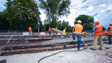 Tramvay rayları onarılan ve bakım süreleri yüksek olan yol inşaatı. Somut, kavşağın ortasında birçok işçiyle birlikte çalışır..