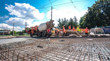 Tramvay rayları onarılan ve bakım süreleri yüksek olan yol inşaatı. Metal bir şebekede mikserden beton dökülüyor. Kavşağın ortası..