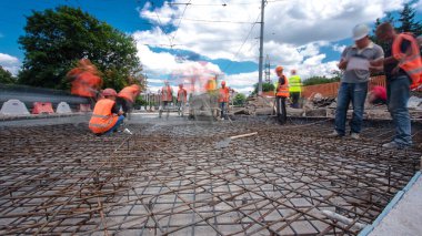 Tramvay rayları onarılan ve bakım süreleri yüksek olan yol inşaatı. Metal bir şebekeye beton dökülüyor. Kavşağın ortası..