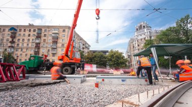 Turuncu vinçle kamyondan beton plakaları indirip yüklüyorlar. Tramvay rayları onarımı ve bakım süreleri olan yol inşaatı kavşağın orta kısmında hızlandırılmış..
