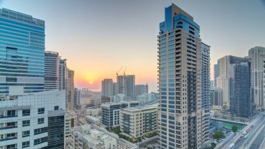 Dubai Yat Limanı hava görünümünü günbatımı timelapse adlı bir noktadan. Modern gökdelenler ve konut kuleleri sıcak akşam ışıkla aydınlatılmış