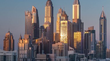 Dubai Yat Limanı günbatımı hava timelapse sırasında Birleşik Arap Emirlikleri kuleleri. Güneş gökdelenler uzun gölgeler ile yansıyan. Yolda trafik ile Jlt üzerinden üstten görünüm
