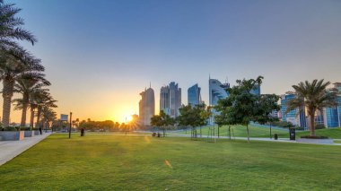 Gün batımında Doha 'nın yüksek katlı zaman diliminde, Hotel Park' tan yeşil çimenli ve ön planda suni tepe ile görüldü. Gökdelenler ve palmiyeler