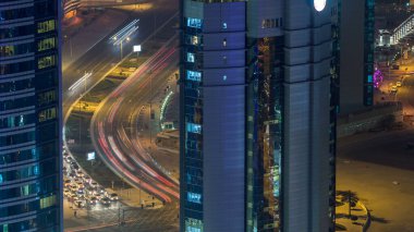 Katar, Doha Timelapse 'da West Bay yolunda trafik var. Aydınlatılmış modern gökdelenler ve gece çatıdan kesişen hava manzarası