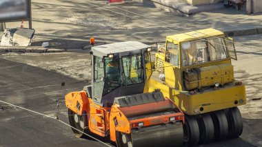 Yeni yol inşaatında çalışan yol silindirlerinin geniş bir manzarası var. Görünümü asfaltlama çalışmaları ile kapat
