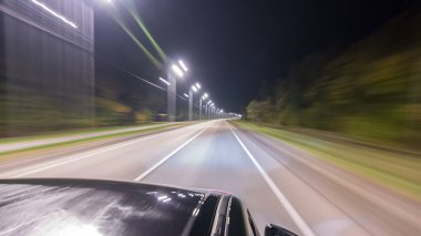 Otobanın en üst kısmından sürtünme gece otobanında süratle ilerliyor. Işıklar arabayı yüksek hızda yansıtıyor. Modern bir şehrin hızlı ritmi. Bulanık hareket