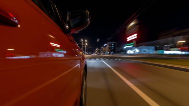 Hızlı arabanın yanından gelen bir drivelapse, gece caddesinde hızla ilerliyor. Işıklar yüksek hızda arabayı yansıtıyor. Modern bir şehrin hızlı ritmi. Bulanık hareket