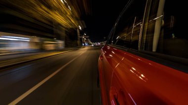 Hızlı arabanın yanından gelen bir saçmalık. Bir gece caddesinde hızla ilerliyor. Işıklar yüksek hızda arabaya yansıyor. Modern bir şehrin hızlı ritmi. Bulanık hareket