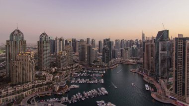 Dubai yat limanı panoraması, gece gündüz tekne ve yat panoraması, geçiş zamanı, aydınlatma ışıkları kapalı, BAE. Gökdelenleri ve kuleleri olan gökyüzü manzarası