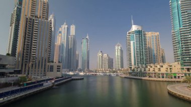 Dubai Marina gökdelenleri, yat ve tekneleri rıhtımda. Köprü zamanından mavi gökyüzü ile hiperhızlandırılmış görüntüle