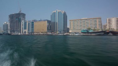 Dubai 'deki Deira Deresi' ndeki Abra gemisinden görüntüler, BAE zaman atlaması. En ucuz nakliye aracı. Rıhtımdaki binalar. Bulanık hareket