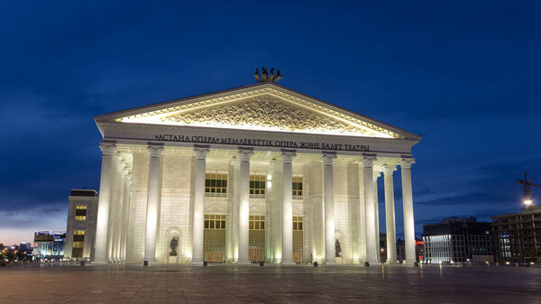State opera and ballet theatre timelapse hyperlapse after sunset. Landmark of Astana, marble building. Night illumination. Nur-Sultan city, Kazakhstan.
