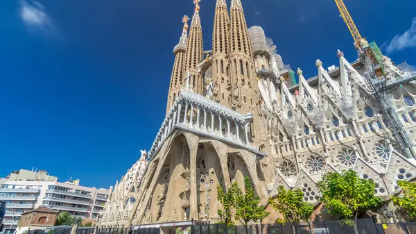 Sagrada Familia: İspanya 'nın Barcelona kentindeki Iconic Roma Katolik Kilisesi' nden Timelapse Hyperlapse. Sonbaharın Zarif Yeşilliği ve Mavi Bulutlu Gökyüzünün Altında Açılan Mimari Mucizeye Şahit Ol.