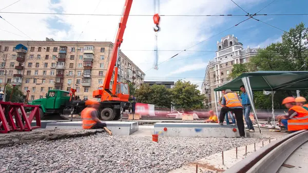 Turuncu vinçle kamyondan beton plakaları indirip yüklüyorlar. Tramvay rayları onarımı ve bakım süreleri olan yol inşaatı kavşağın orta kısmında hızlandırılmış..