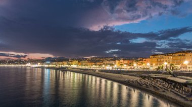 Waterfront güzel şehir ve Akdeniz deniz gün gece geçiş timelapse için. Bay of Angels yansıması su, Cote d'Azur, French Riviera, Fransa ile gezinti dramatik gökyüzü ile