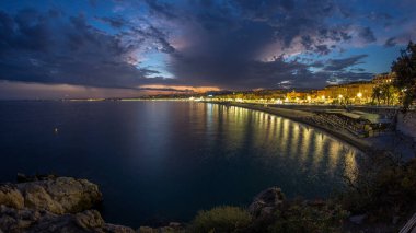Waterfront güzel şehir ve Akdeniz deniz gün gece geçiş timelapse için. Bay of Angels yansıması su, Cote d'Azur, French Riviera, Fransa ile gezinti dramatik gökyüzü ile