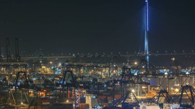 Geceleyin Hong Kong Konteynır Terminali 'nde, arka planda köprüyle birlikte. Kwai Tsing Konteynır Terminalleri dünyanın en işlek limanlarından biridir. Konteynır gemileri yükleniyor ve boşaltılıyor