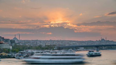 İstanbul 'un ufuk çizgisi İstanbul' da, günbatımında Boğaziçi ve Altın Boynuz 'daki tekne istasyonu yakınlarında çok sayıda yolcu feribotu bulunuyor. Arka planda cami ve köprü, bahar akşamında suyun yansımasıyla