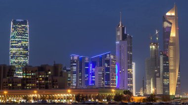 Kuwait City skyline with Skyscrapers day to night transition timelapse in downtown illuminated at dusk. Kuwait City, Middle East. View from road clipart