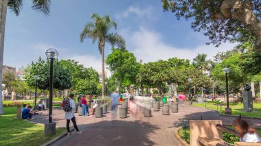 Miraflores Central Park zaman atlamalı yeşil ağaçlar ve Peru başkentindeki çimlerle dinlenmek için bir yer. İnsanlar banklarda oturup yürüyorlar. Lima, Peru