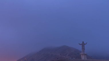 Aerial view of Cristo del Pacifico and Morro Solar hill in the background night to day transition timelapse. Foggy weather early morning before sunrise clipart