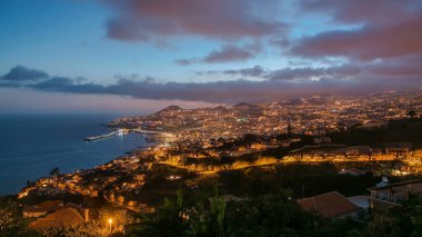 Gün batımından sonra adanın manzarası Funchal 'a gündüz, gece geçişi, Madeira, Portekiz zaman çizelgesi. Limanda akşam aydınlatması ve şehir ışıklarıyla