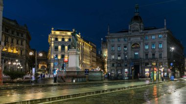 Cordusio Meydanı ve Dante Caddesi çevresindeki saraylar, evler ve binalar İtalyan moda ve lüks başkentinde gece panoramik. Yazar ve şair Giuseppe Parini anıtı. Tramvaylar geçiyor.